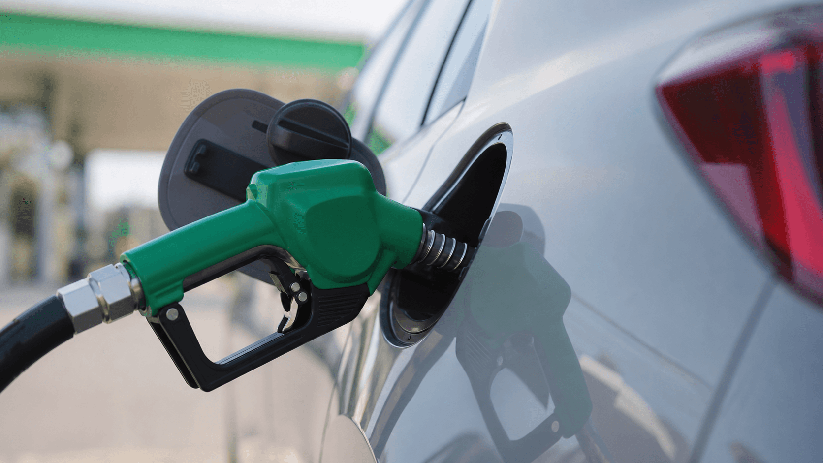 Bico verde de bomba abastecendo um carro em posto de gasolina